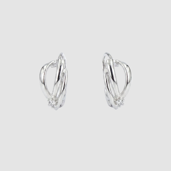 A pair of silver-toned huggie hoop earrings with a small cluster of clear stones at the bottom of each earring, shown on a plain white background.
