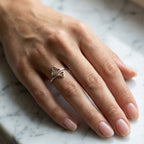 Hand wearing a silver ring on a marble surface