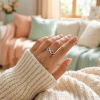 Hand wearing an infinity ring with a cozy living room background