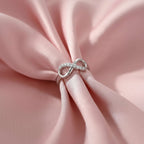 Silver ring with diamonds on a pink fabric background