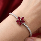 Bracelet with a red gemstone flower design on a wrist against a red background