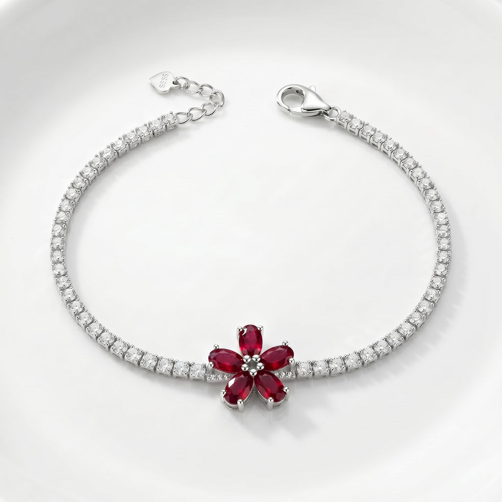 Silver bracelet with a red gemstone flower design on a white background