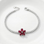 Silver bracelet with a red gemstone flower design on a white background