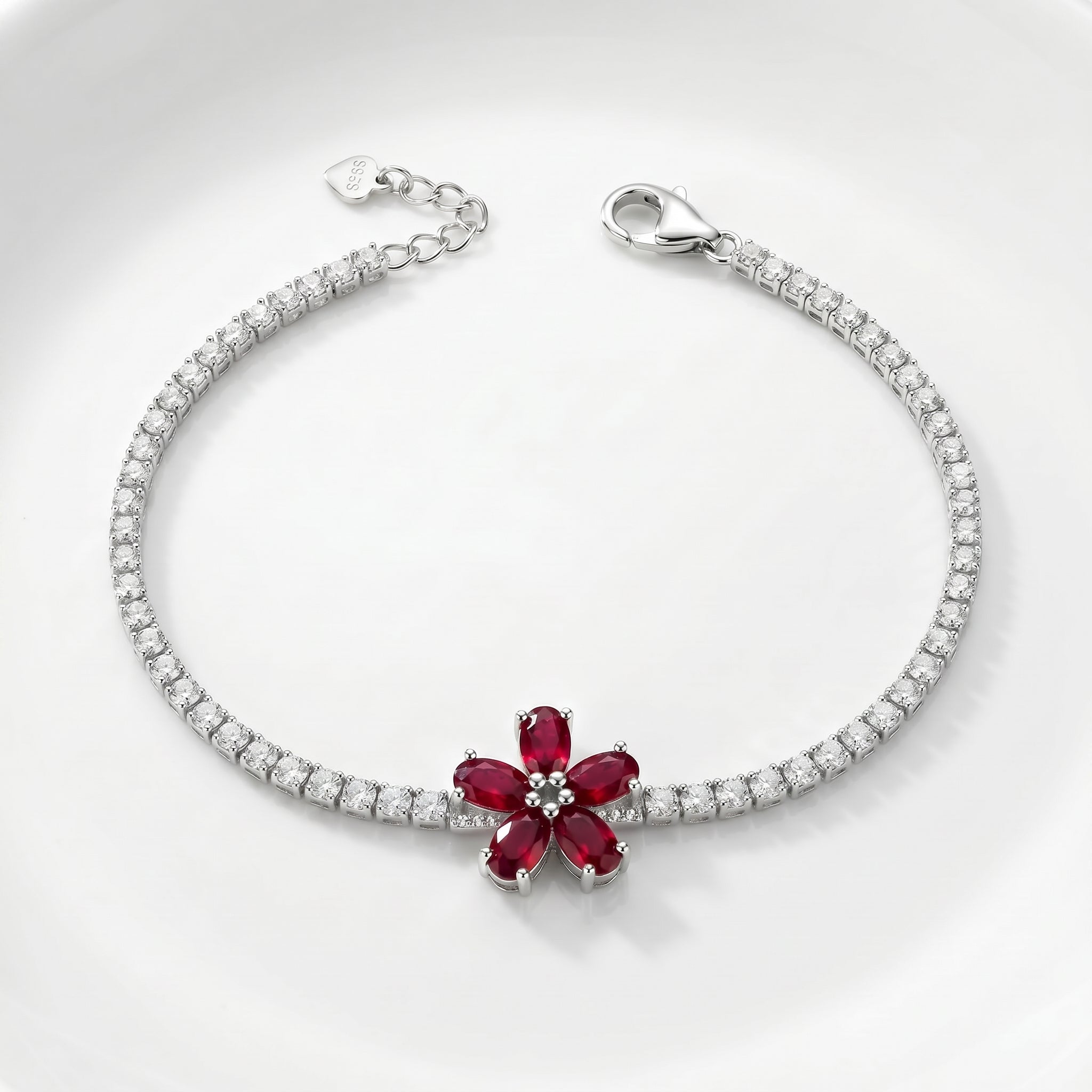 Silver bracelet with a red gemstone flower design on a white background