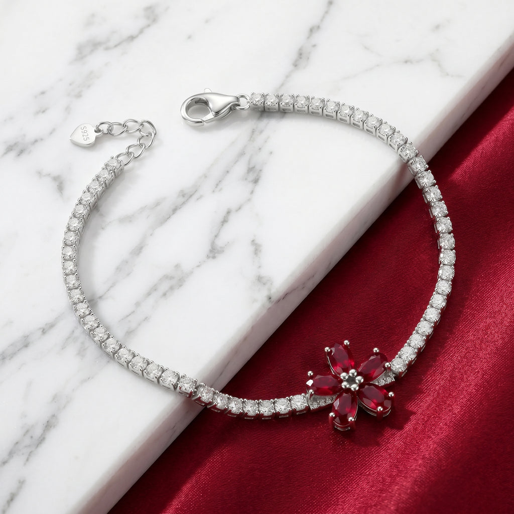 Silver bracelet with a red flower-shaped gemstone on a marble and red fabric background