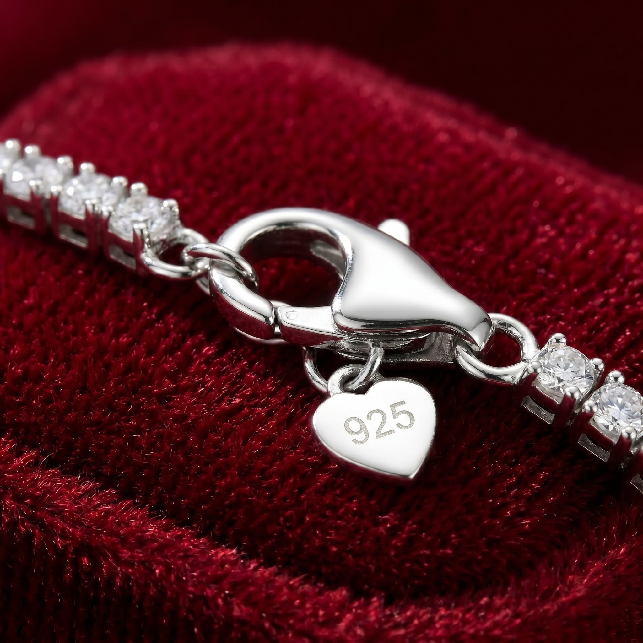 Silver bracelet with a heart-shaped charm displaying '925' on a red velvet background