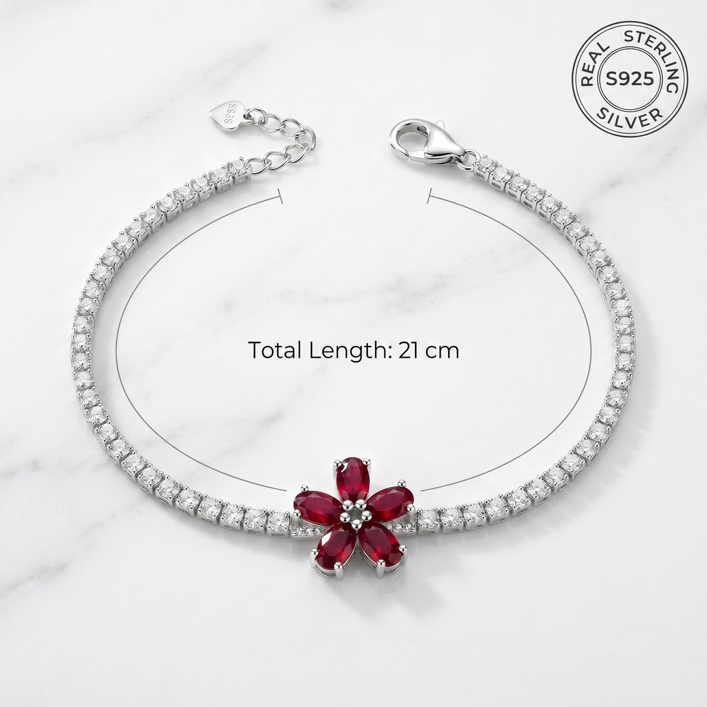 Silver bracelet with a red gemstone on a white marble background