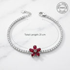 Silver bracelet with a red gemstone on a white marble background