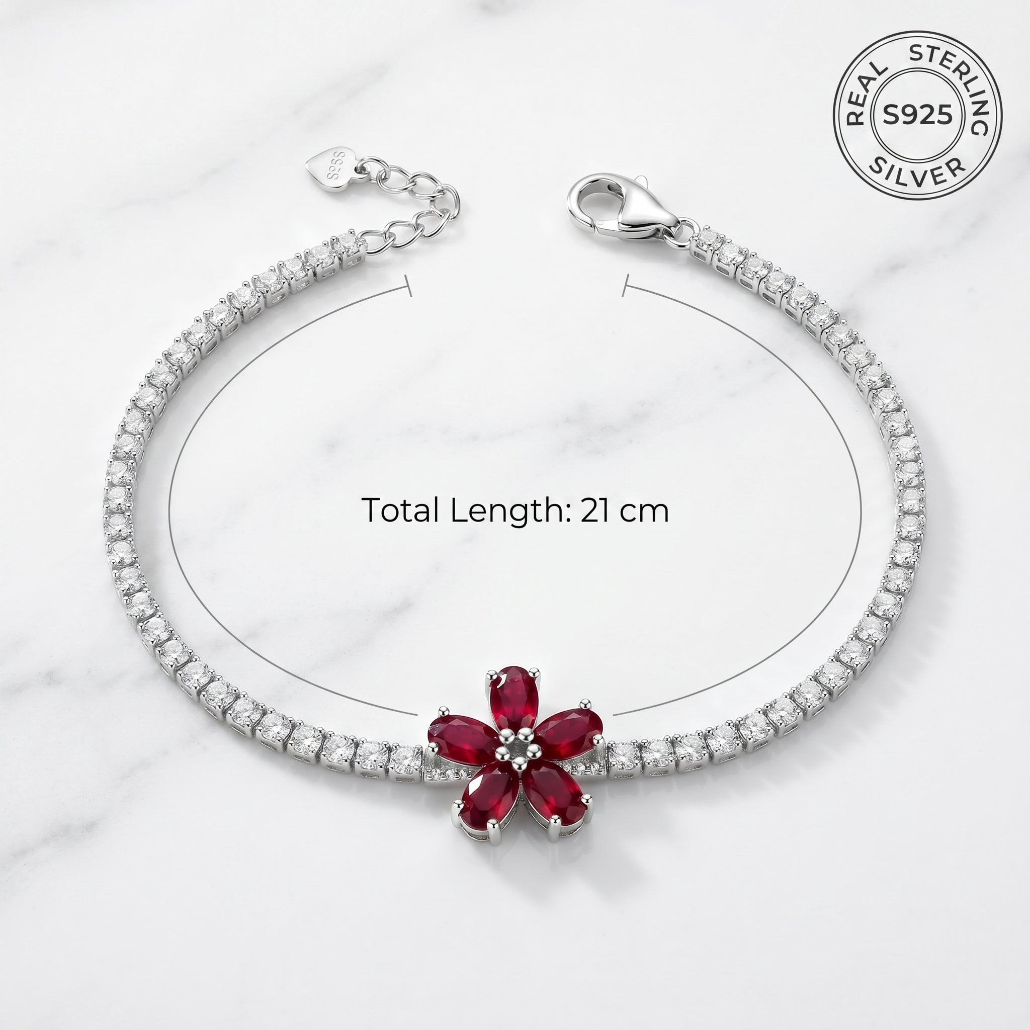 Silver bracelet with a red gemstone on a white marble background