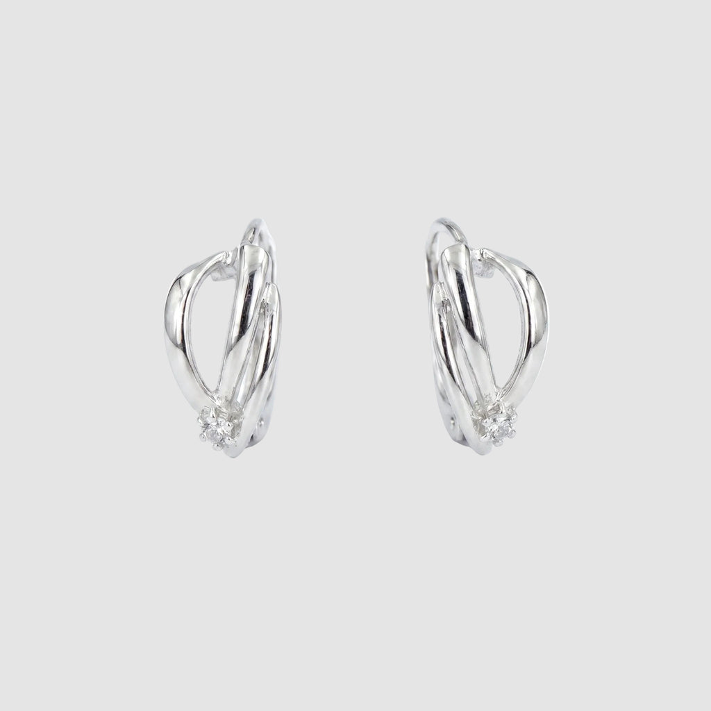 A pair of silver-toned huggie hoop earrings with a small cluster of clear stones at the bottom of each earring, shown on a plain white background.